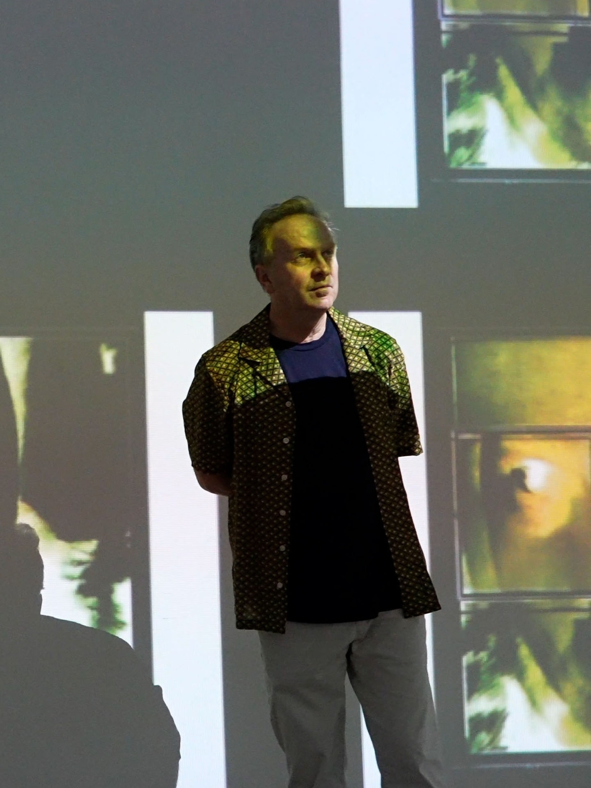 Medium-long shot of Pierre Tremblay in front of a projected art piece.